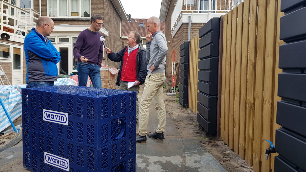 Interview bij woningproject met vier personen naast wateropvangkratten en regenwatersysteem