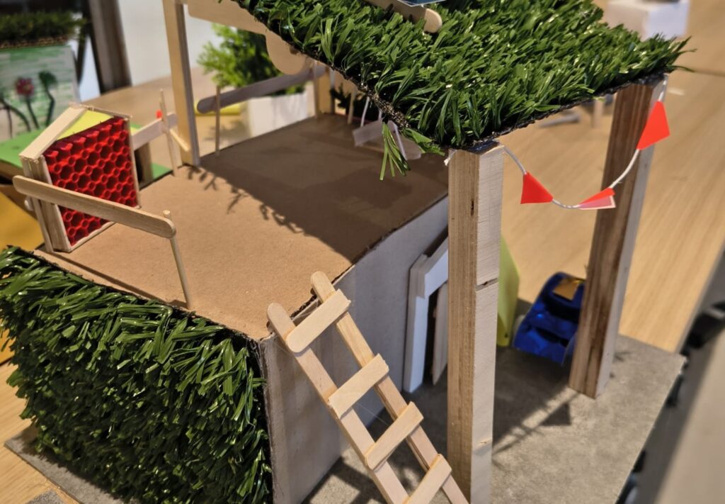 Maquette van woning met groen dak en duurzame elementen op een tafel